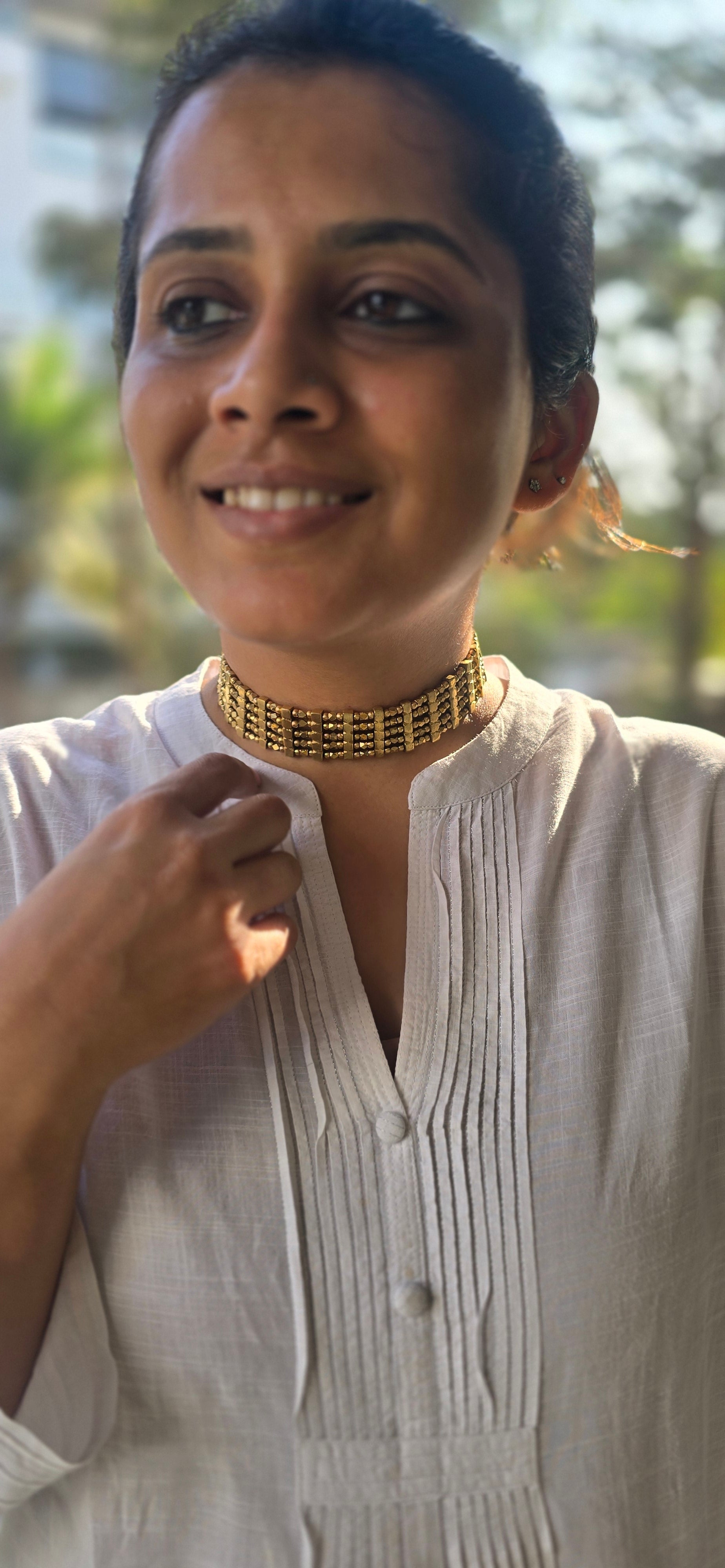 Person wearing a brass choker with a blurred background