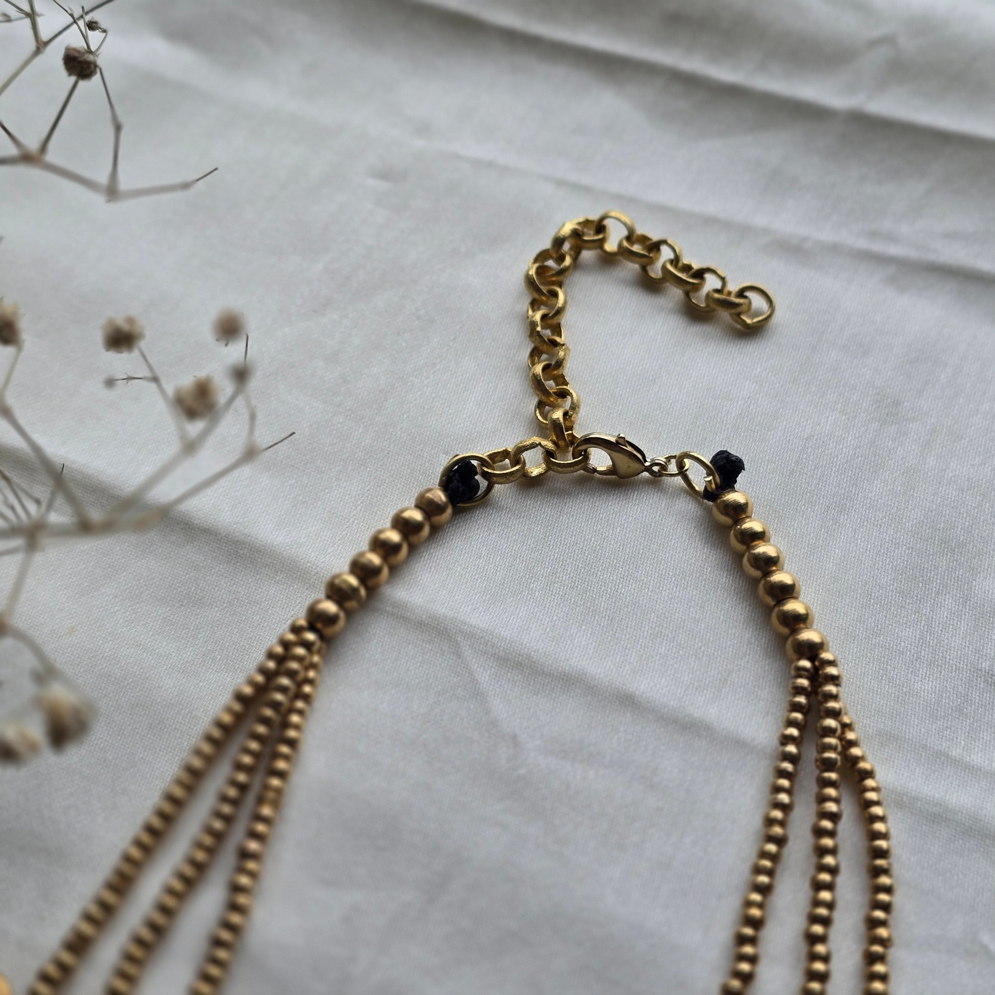 Brass chain necklace with layers of necklace on a light fabric background