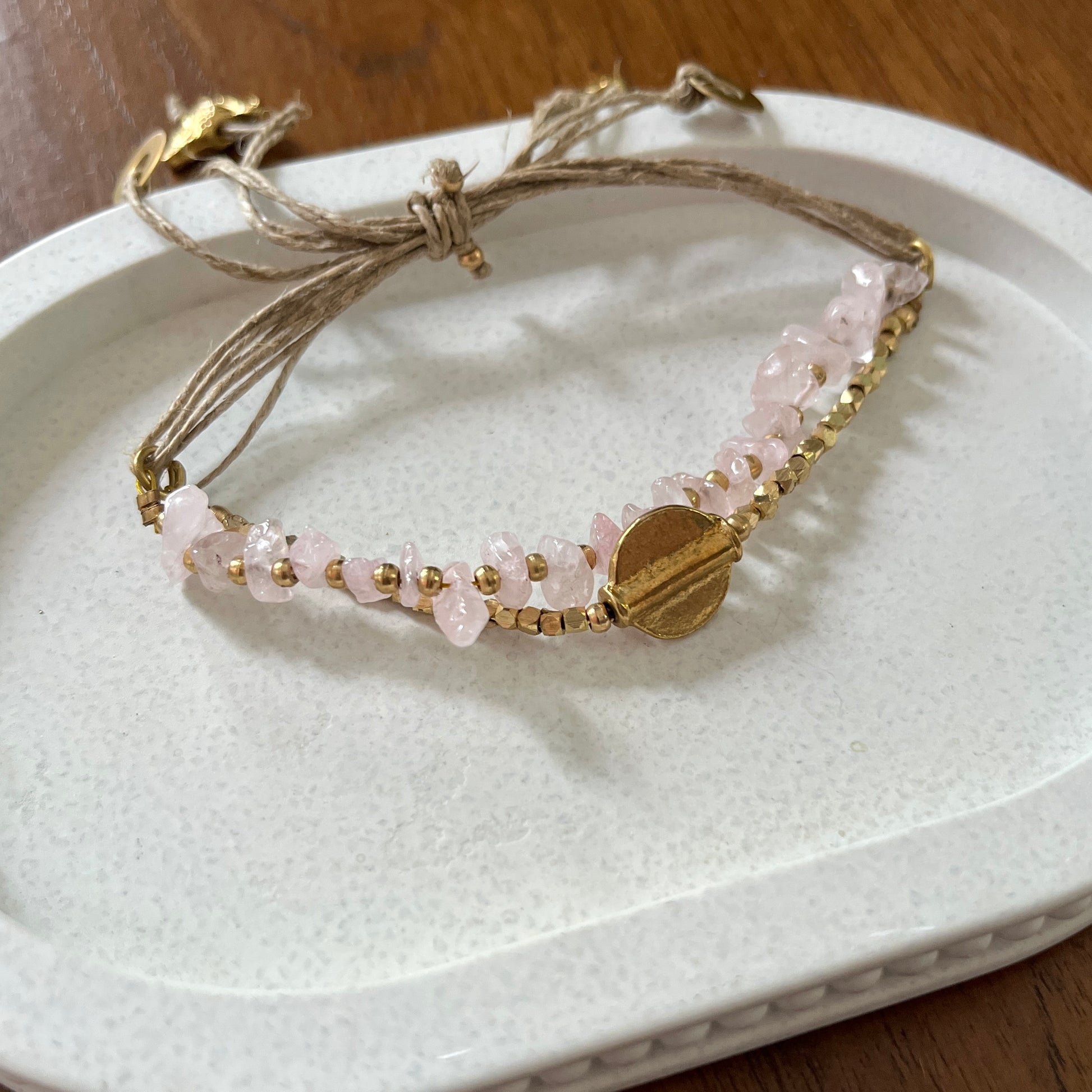 Bracelet with pink beads and gold accents on a white dish