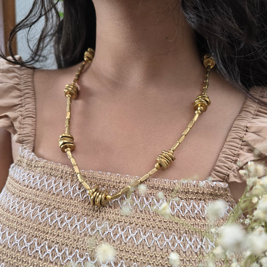 Brass neckpiece worn by a person with a blurred background