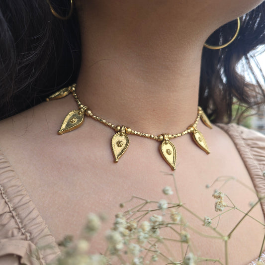 Brass leaf anklet on a person's neck with a blurred background