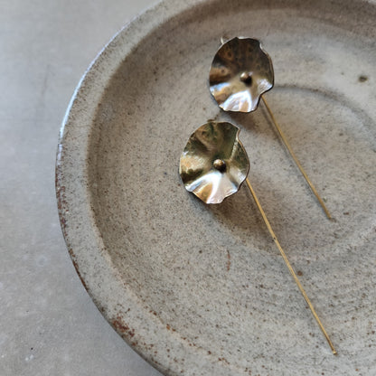 Pair of gold earrings on a textured ceramic plate